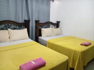 2 camas con sábanas amarillas y una toalla morada. en Historico maya, en Guatemala