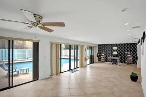 a living room with a ceiling fan and a pool at Stylish palm beach home with pool and office in Palm Beach Gardens