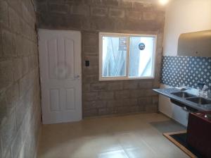 uma casa de banho com uma porta, um lavatório e uma janela em Monoambientes Chamical em Chamical