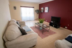 a living room with a couch and a tv at Casa da Carmita in Angra do Heroísmo