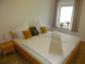 łóżko z białą pościelą i poduszkami oraz oknem w obiekcie Ferienwohnung Schusternagerl w mieście Simbach