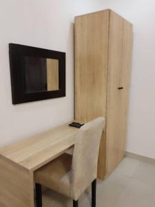 a wooden desk with a chair and a television on a wall at Zek’s Place in Ikeja