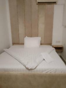 a bed with white sheets and a pillow at Zek’s Place in Ikeja