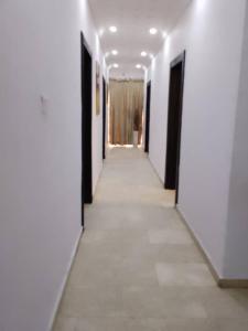 un couloir avec des murs blancs et une rangée de portes dans l'établissement Zek’s Place, à Ikeja