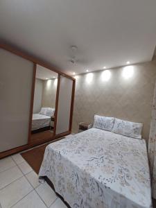 um quarto com uma cama e um espelho grande em Apartamento com AR Condicionado, Condomínio aconchegante com piscina 2 Qts em Serra