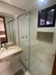 y baño con ducha acristalada y lavamanos. en Crystal Place - Studio Alessandra Antonelli - flat 1710, en Goiânia