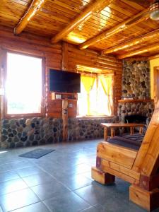 ein Wohnzimmer in einem Blockhaus mit einem TV in der Unterkunft Cabañas franlu in Lago Puelo