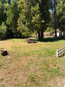 um parque com um banco e mesas de piquenique na relva em Cabañas franlu em Lago Puelo