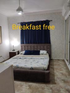 1 dormitorio con cama con cartel de desayuno gratuito en Nely y Pietro share apartment, en Punta Cana