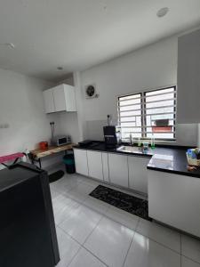 a kitchen with white cabinets and black counter tops at Thetamu Homestay مسلم Kepala Batas in Kepala Batas