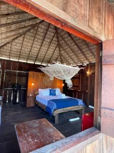 a bedroom with a bed in a straw roof at Atins Beach Chalés in Atins