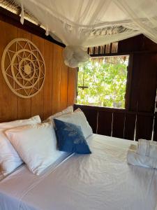 1 cama con sábanas blancas y almohadas azules en Atins Beach Chalés, en Atins