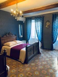 een slaapkamer met een groot bed en blauwe gordijnen bij La Babayaga in Capestang