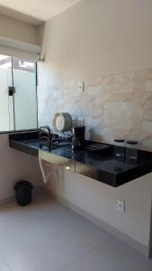 a kitchen counter with a sink and a mirror at Morada do Sol Suítes in Arraial do Cabo