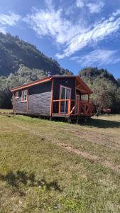 a small cabin in the middle of a field at Cabaña Cordillera in Cochamó +15 photos