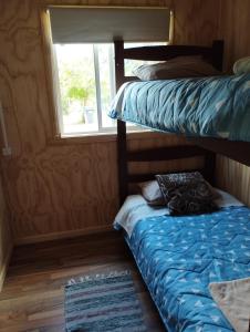 two bunk beds in a room with a window at Cabaña Cordillera in Cochamó