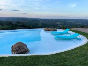 a swimming pool with two chairs and a rock at Casa Pedra da Lua, uma casa para contemplar o agreste. in Gravatá