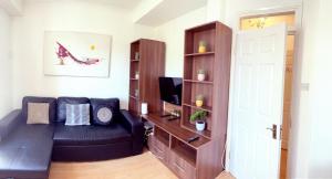 ein Wohnzimmer mit einer schwarzen Couch und einem Bücherregal in der Unterkunft UK CHAPS Retreat: 2 Bedroom - 2Bathroom Apartment in London
