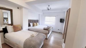 a white room with two beds and a couch at UK CHAPS Retreat: 2 Bedroom - 2Bathroom Apartment in London