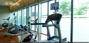 una palestra con macchinari per il cardio-fitness in un edificio con finestre di St Moritz Apartment Puri Indah a Giacarta