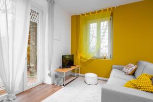 a yellow living room with a couch and a television at Cascina Conicchio - Metro Station - by Host4U in Brescia