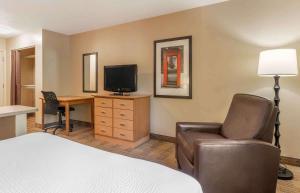 a hotel room with a bed and a desk with a television at Extended Stay America Select Suites - St Louis - Westport - Craig Road in Maryland Heights