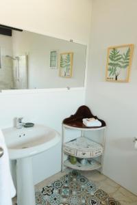 een witte badkamer met een wastafel en een spiegel bij Villa Bougainvillea Aruba Rumba Suite in Palm-Eagle Beach