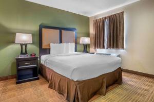 Extended Stay America Select Suites - Greenville - Haywood Mall في غرينفيل: سرير كبير في غرفة بها مصباحين