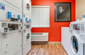 a laundry room with orange walls and white appliances at Studio 6 Extended Stay Florence KY - Meijer Dr Cincinnati in Florence