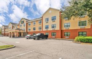 un coche aparcado en un aparcamiento frente a un edificio en Extended Stay America Select Suites - Tampa - North - USF - Attractions, en Tampa