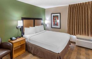 ein Hotelzimmer mit einem großen Bett und einem Stuhl in der Unterkunft Extended Stay America Suites - Auburn Hills - University Drive in Auburn Hills