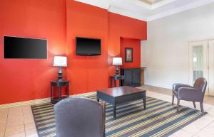Extended Stay America Suites - Dallas - DFW Airport N في ايرفينغ: غرفة معيشة بجدران حمراء وطاولة وكراسي