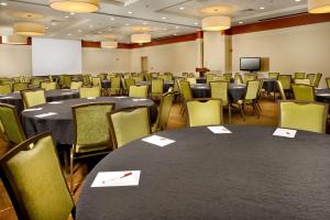 una sala conferenze con tavoli, sedie e schermo di Drury Inn & Suites Valdosta a Valdosta