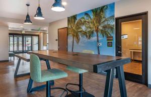 GibsontonにあるExtended Stay America Premier Suites - Tampa - Gibsonton - Riverviewの大きな木製テーブル(椅子付)とヤシの木の壁画