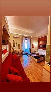 ナポリにあるCorso 211 Beds & Suitesのベッド2台とソファが備わる広い客室です。