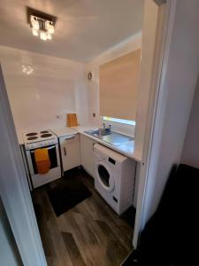 a small kitchen with a sink and a washing machine at Sleek & Stylish - E15 Apartment With Parking in London