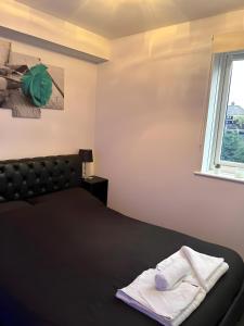 a bedroom with a black bed and a window at Sleek & Stylish - E15 Apartment With Parking in London