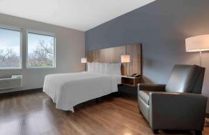 1 dormitorio con 1 cama blanca y 1 silla en Extended Stay America Premier Suites - Austin - Austin Airport, en Austin