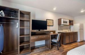 a hotel room with a desk with a television and a bed at Extended Stay America Select Suites - Tampa - Brandon - East in Tampa