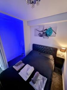una camera da letto con un letto nero con due cuscini sopra di Sleek & Stylish - E15 Apartment With Parking a Londra