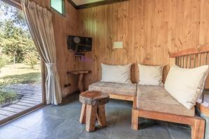 Habitación con sofá, mesa y TV. en Cabañas Pucon Location, en Pucón