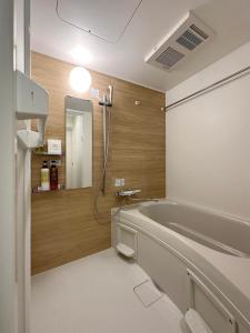 La salle de bains est pourvue d'une baignoire et d'un miroir. dans l'établissement bHOTEL Nikke - Spacious Apt for 12Ppl Very Good Location, à Ōsukachō