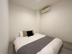 a bedroom with a white bed with a black pillow at bHOTEL Nikke - Apt for 10Ppl Ideal for Big Group in City Center in Ōsukachō