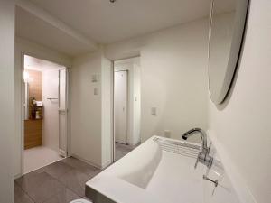 a white bathroom with a sink and a mirror at bHOTEL Nikke - Apt for 10Ppl Ideal for Big Group in City Center in Ōsukachō