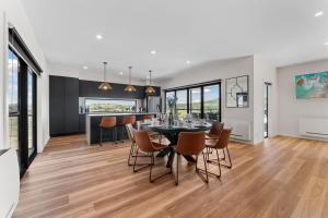 Un comedor y una cocina con mesa y sillas. en 1B Alpine View Retreat - 4BR Luxurious Escape l Mountain Views l Fast WiFi, en Jindabyne