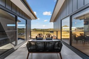 Una habitación con una mesa y sillas en un balcón. en 1B Alpine View Retreat - 4BR Luxurious Escape l Mountain Views l Fast WiFi, en Jindabyne