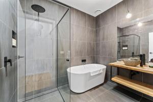 un baño con ducha y bañera en 1B Alpine View Retreat - 4BR Luxurious Escape l Mountain Views l Fast WiFi, en Jindabyne 22 fotos más