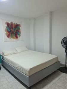 a bed in a bedroom with a white wall at Hostal Casa Yare in Rodadero