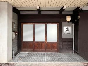 a door to a building with a sign on it at Hostel Murasaki Ryokan Miyagawa in Takayama