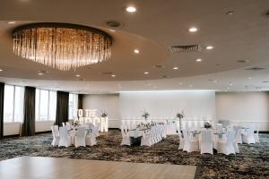 スーフォールズにあるHoliday Inn Sioux Falls-City Center, an IHG Hotelの白いテーブルと椅子、シャンデリアのある宴会場